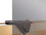 Närbild: grå glasbastudörr med vikhandduk på insidan